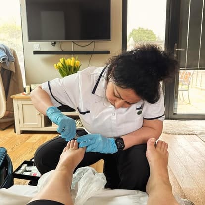 Kam, a foot health practitioner, treating a client's feet during a home visit